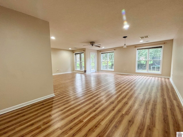 unfurnished living room featuring ceiling fan, a textured ceiling, and light hardwood / wood-style floors