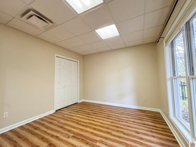 empty room with a paneled ceiling and hardwood / wood-style floors