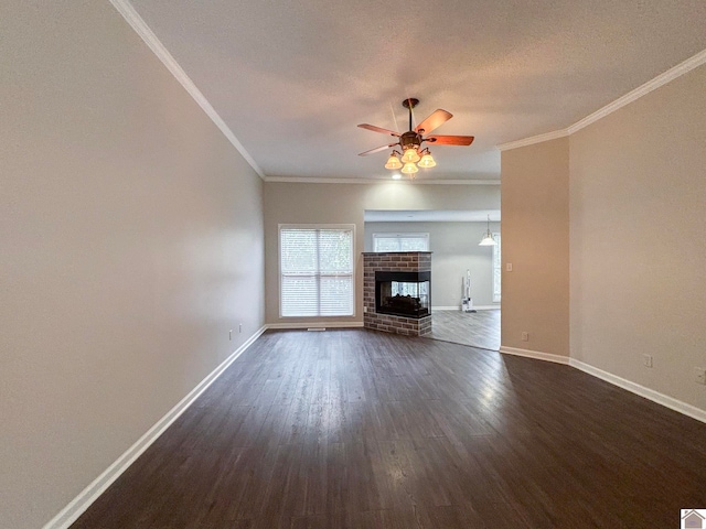 unfurnished living room with ornamental molding, a fireplace, dark wood-type flooring, and ceiling fan