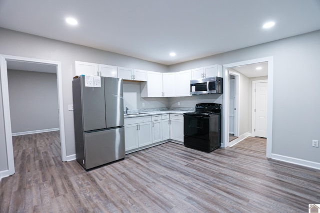 kitchen with white cabinetry, appliances with stainless steel finishes, sink, and light wood-type flooring