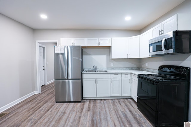 kitchen featuring stainless steel appliances, light hardwood / wood-style floors, white cabinetry, and sink