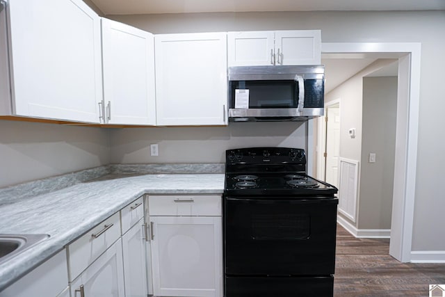 kitchen with black electric range, dark hardwood / wood-style flooring, and white cabinetry