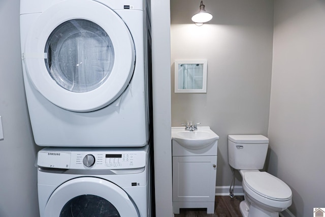 laundry room with stacked washer / drying machine, dark wood-type flooring, and sink