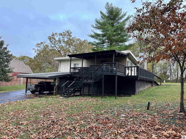 back of house with a deck, a lawn, and a carport