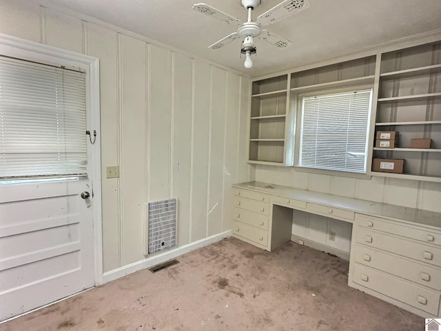 unfurnished office with light carpet, built in desk, and ceiling fan