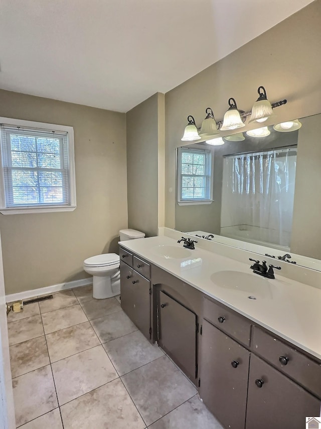 bathroom with toilet, vanity, tile patterned flooring, and plenty of natural light