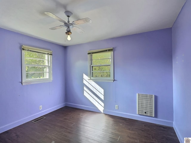 spare room with ceiling fan, dark hardwood / wood-style floors, and heating unit