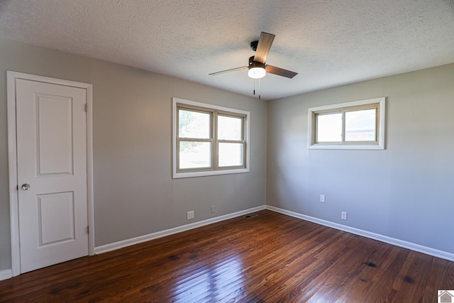 empty room with dark wood-style flooring, plenty of natural light, and baseboards