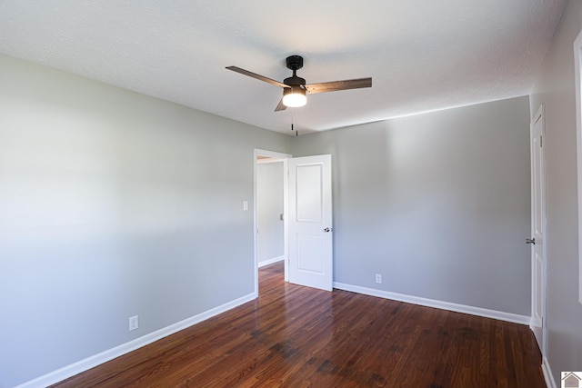 empty room featuring a ceiling fan, a textured ceiling, baseboards, and dark wood-style floors