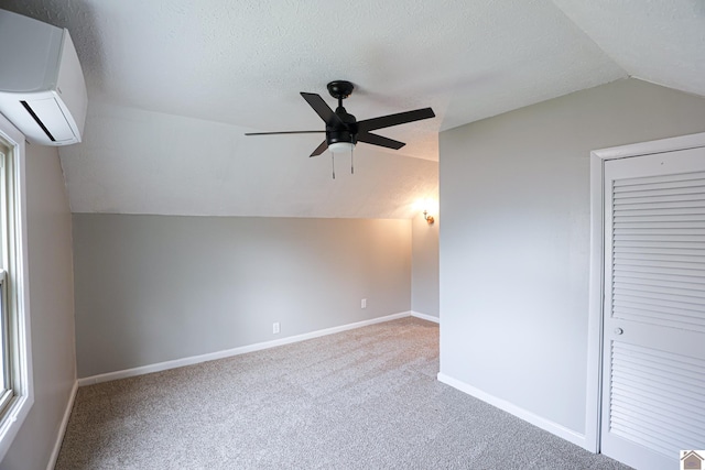 bonus room featuring carpet, a wall unit AC, lofted ceiling, a textured ceiling, and baseboards