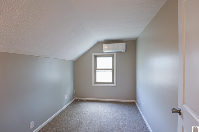 bonus room with a wall unit AC, lofted ceiling, carpet flooring, a textured ceiling, and baseboards