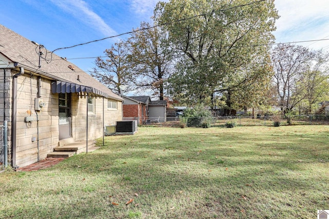 view of yard with entry steps, a fenced backyard, and central AC unit