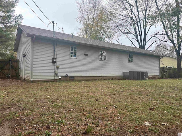 back of property featuring central air condition unit and a yard