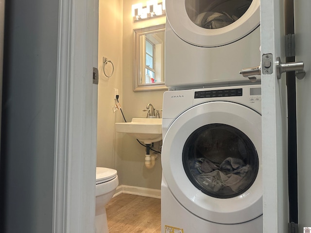 laundry area featuring hardwood / wood-style floors and stacked washer and clothes dryer