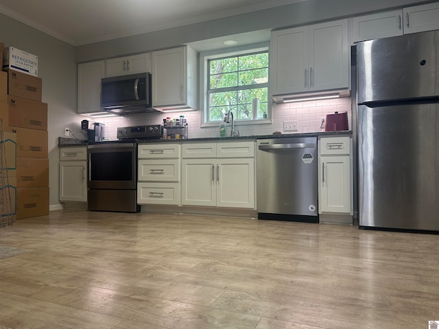 kitchen featuring white cabinets, stainless steel appliances, and crown molding