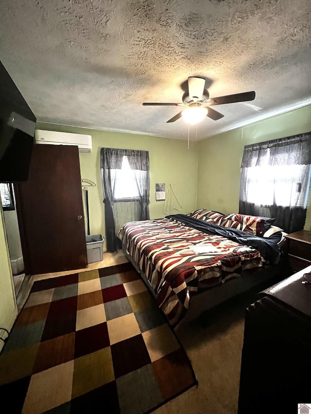 bedroom with a textured ceiling, a wall mounted air conditioner, and ceiling fan