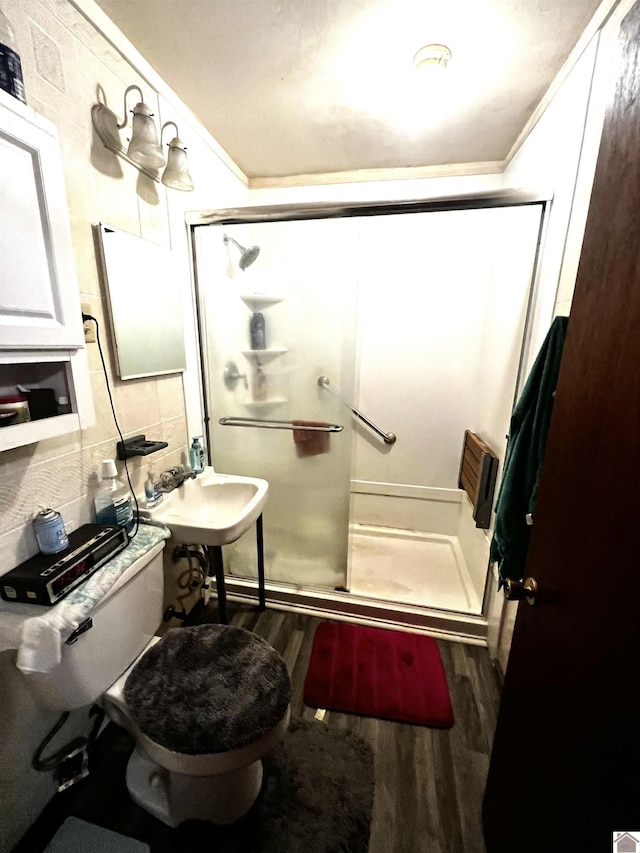 bathroom with hardwood / wood-style floors, toilet, an enclosed shower, and decorative backsplash