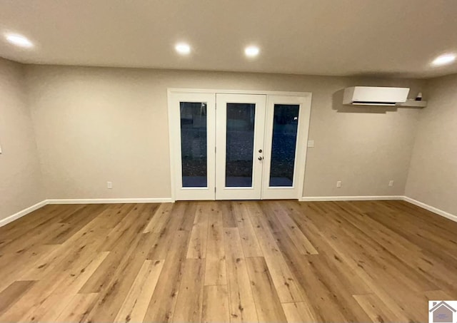 spare room featuring a wall mounted AC and light hardwood / wood-style flooring