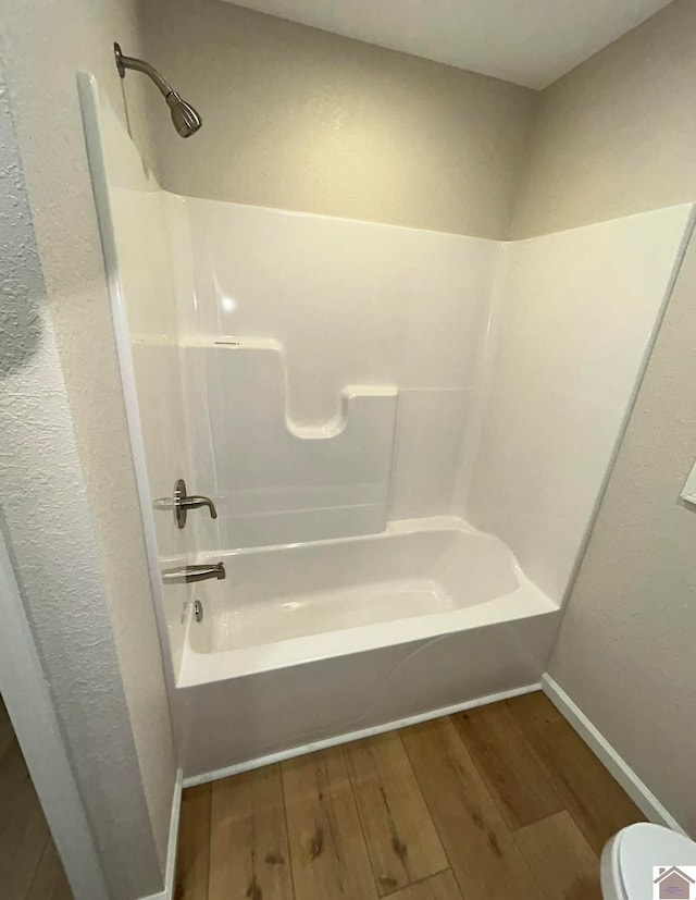 bathroom with hardwood / wood-style floors, shower / tub combination, and toilet