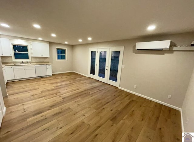 unfurnished living room featuring sink, light hardwood / wood-style flooring, and a wall mounted air conditioner