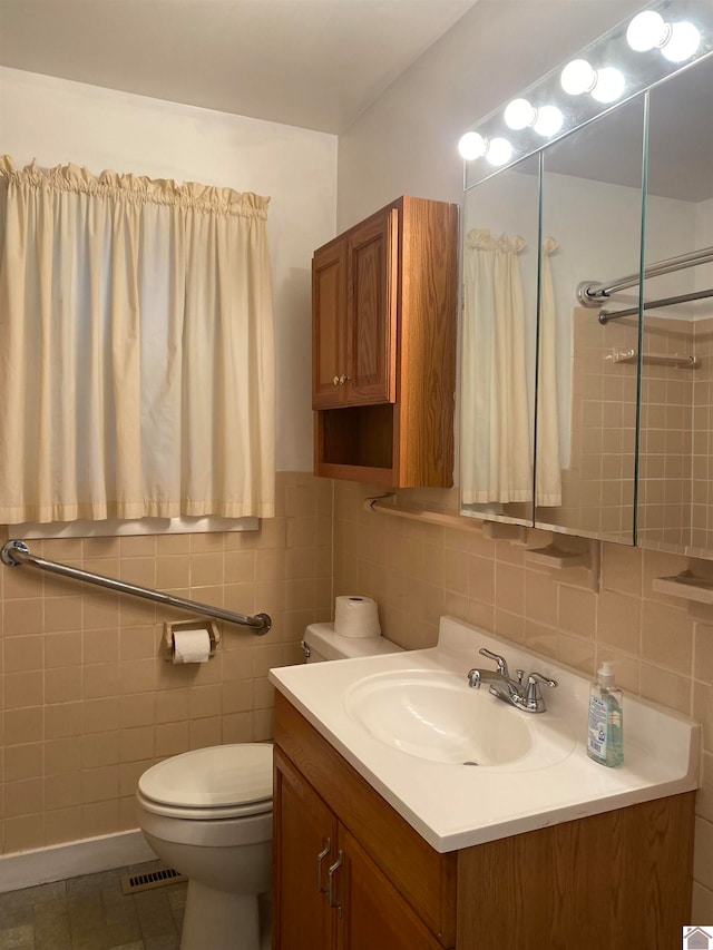 bathroom with tile patterned flooring, vanity, toilet, and tile walls