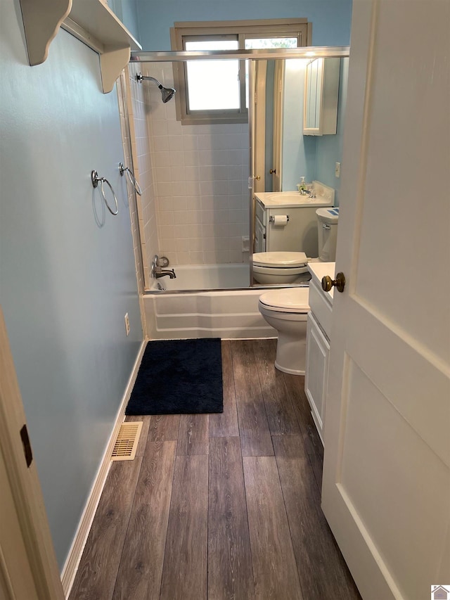 full bathroom featuring toilet, vanity, enclosed tub / shower combo, and hardwood / wood-style flooring