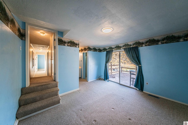 carpeted empty room featuring a textured ceiling