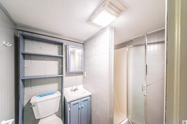 bathroom featuring vanity, a textured ceiling, toilet, and a shower with door