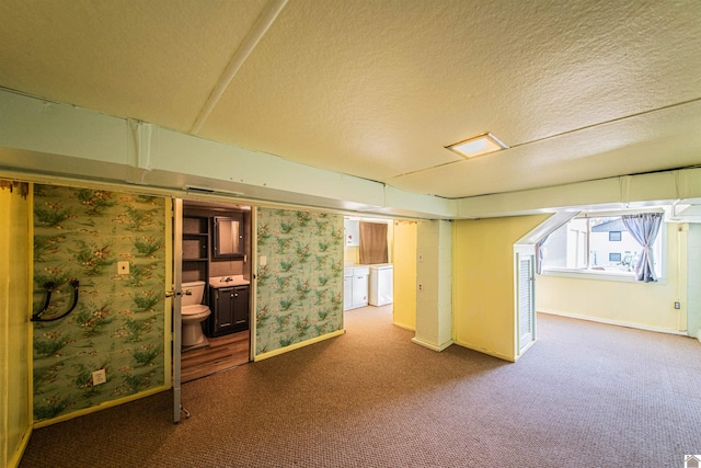 basement with a textured ceiling, carpet floors, and washer and clothes dryer