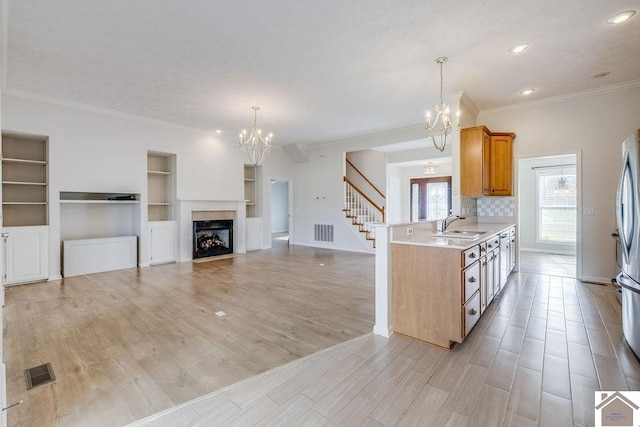 kitchen featuring built in features, kitchen peninsula, hanging light fixtures, and light hardwood / wood-style flooring