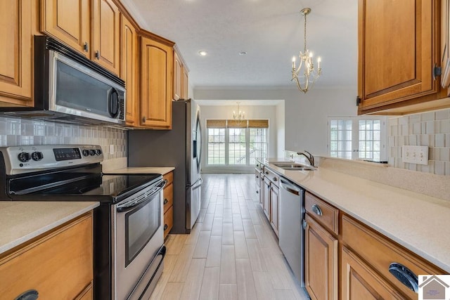 kitchen featuring stainless steel appliances, an inviting chandelier, sink, crown molding, and decorative light fixtures