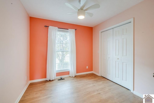 unfurnished bedroom featuring ceiling fan, multiple windows, and light wood-type flooring