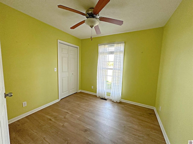 unfurnished bedroom with a closet, a textured ceiling, ceiling fan, and light hardwood / wood-style flooring