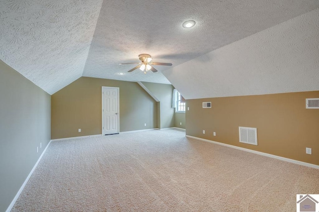 bonus room featuring ceiling fan, light colored carpet, a textured ceiling, and lofted ceiling