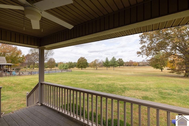 wooden terrace featuring ceiling fan, a yard, and a rural view