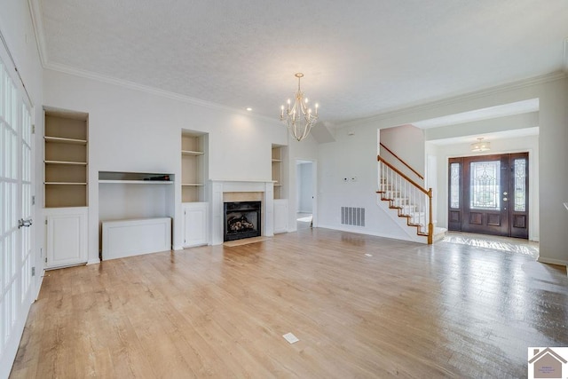 unfurnished living room featuring crown molding, light wood-type flooring, and built in shelves