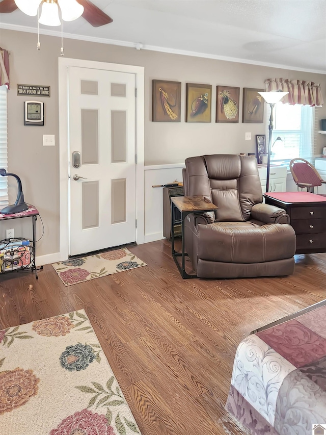 living room featuring wood-type flooring, ceiling fan, and crown molding