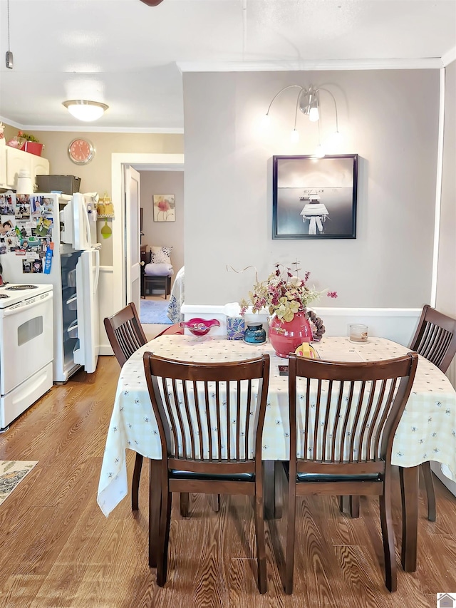 dining space featuring light wood-type flooring and ornamental molding