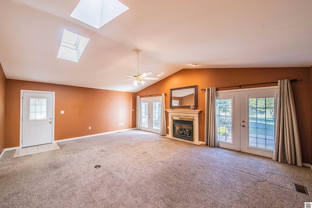 unfurnished living room featuring ceiling fan, carpet floors, lofted ceiling, a tile fireplace, and french doors