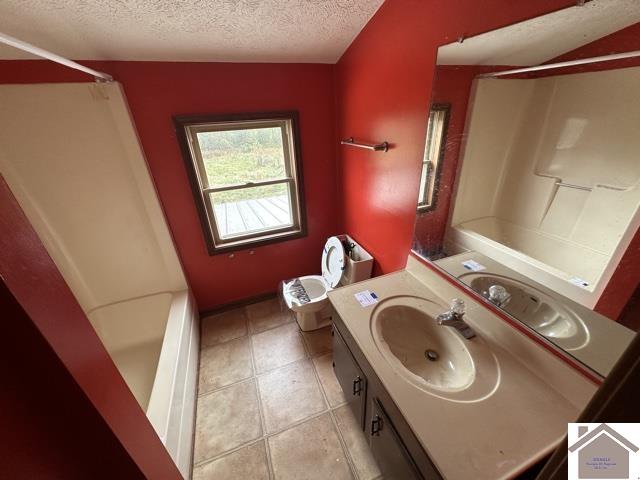 bathroom with vanity, a textured ceiling, tile patterned floors, and  shower combination