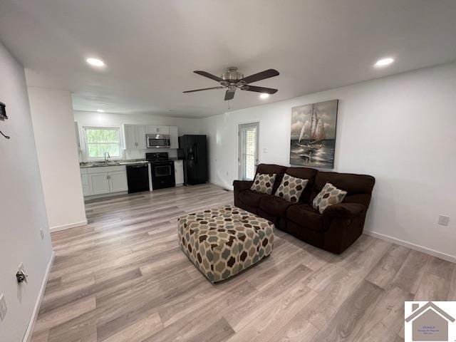 living room featuring light hardwood / wood-style flooring, ceiling fan, and sink