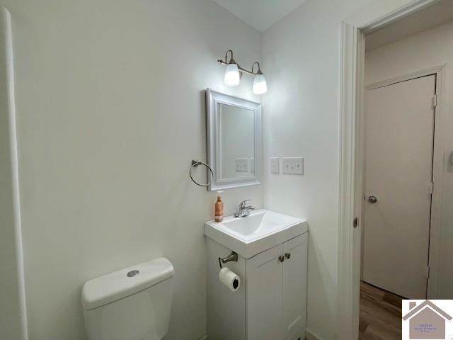 bathroom featuring wood-type flooring, vanity, and toilet