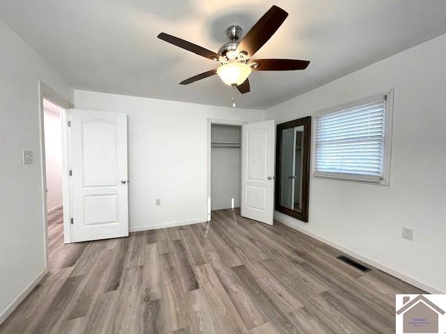 unfurnished bedroom with light hardwood / wood-style flooring, ceiling fan, and a closet