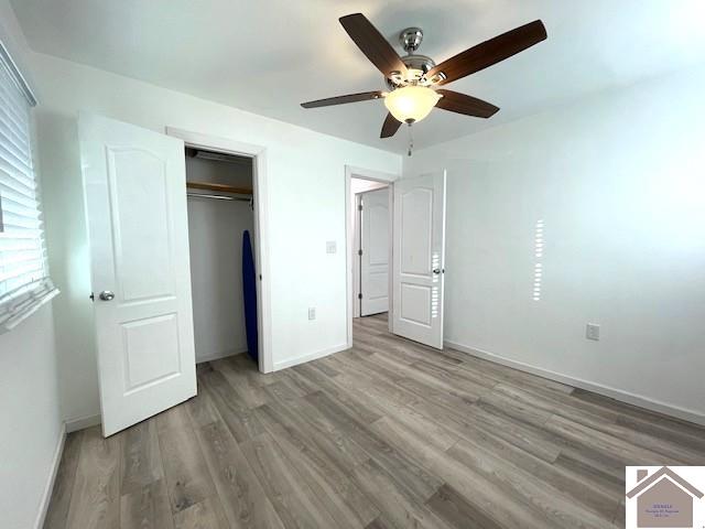 unfurnished bedroom with wood-type flooring, ceiling fan, and a closet