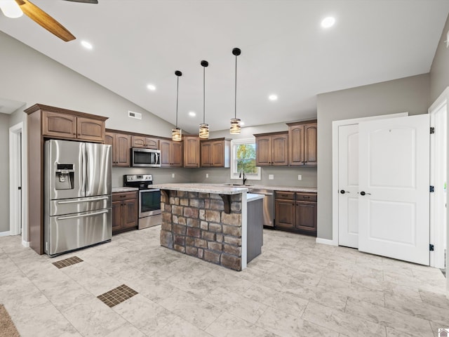 kitchen featuring stainless steel appliances, dark brown cabinetry, hanging light fixtures, lofted ceiling, and a center island