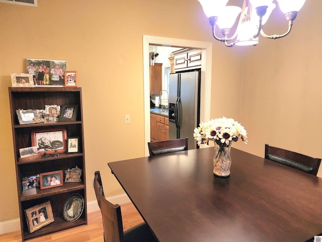 dining space featuring light hardwood / wood-style flooring, a chandelier, and sink