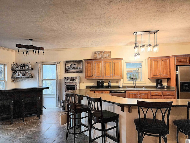 kitchen featuring a kitchen bar, a textured ceiling, stainless steel appliances, sink, and pendant lighting