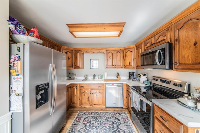 kitchen featuring a skylight, sink, stainless steel appliances, and light wood-type flooring