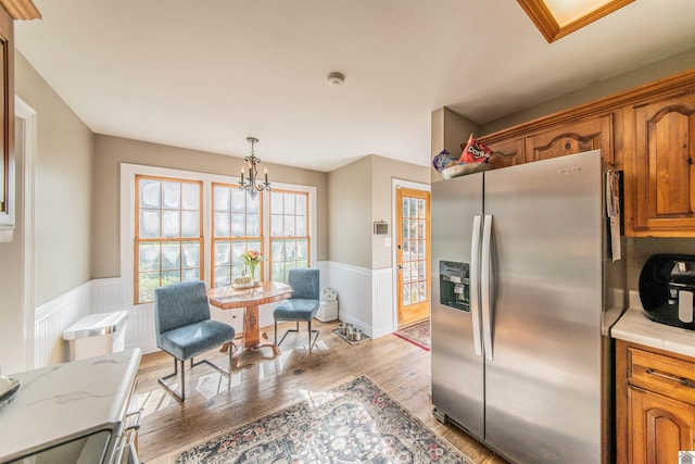 kitchen featuring stainless steel fridge, light wood-type flooring, decorative light fixtures, and an inviting chandelier