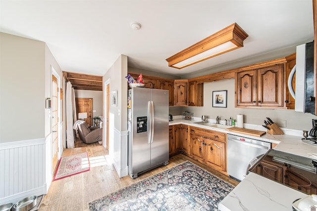 kitchen with appliances with stainless steel finishes, light hardwood / wood-style floors, and sink